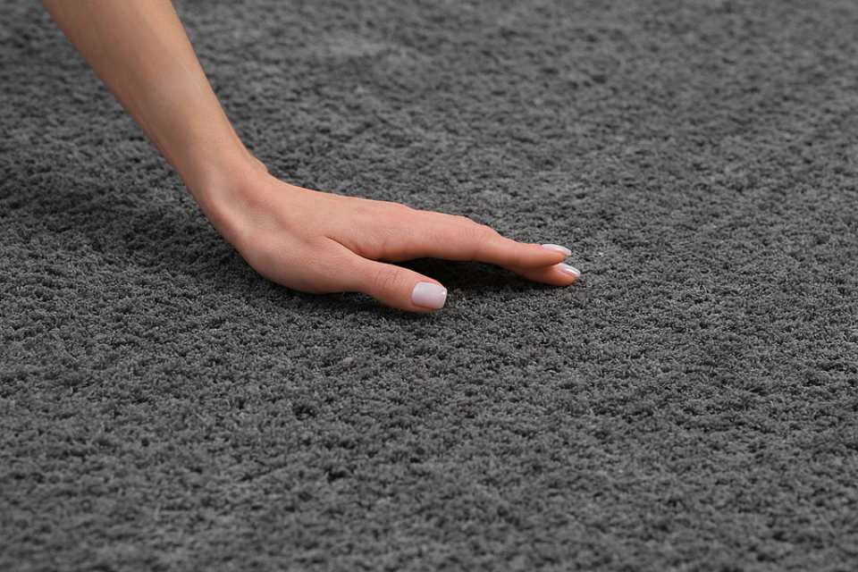 female hand touching new soft grey carpet